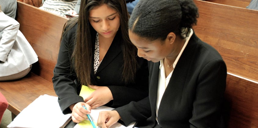 narrow two students conferring over notes mock trial